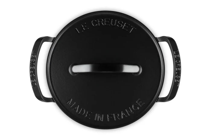A black Le Creuset round lidded pot shown from a top-down view on a white background, featuring embossed branding and the text 'MADE IN FRANCE'.