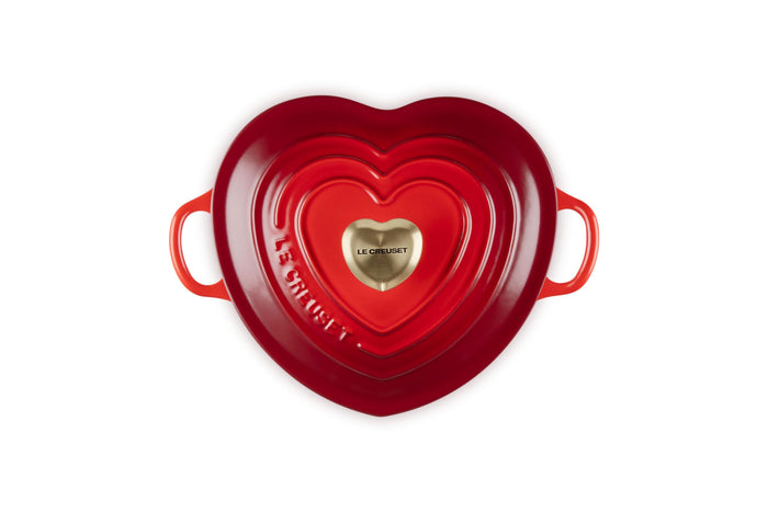 Top view of cerise heart shaped 1.25 qt cocotte with handles and a light gold heart knob displayed on a white background