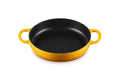 A round cast iron skillet with a yellow exterior and a black non-stick interior, featuring two loop handles on a white background.