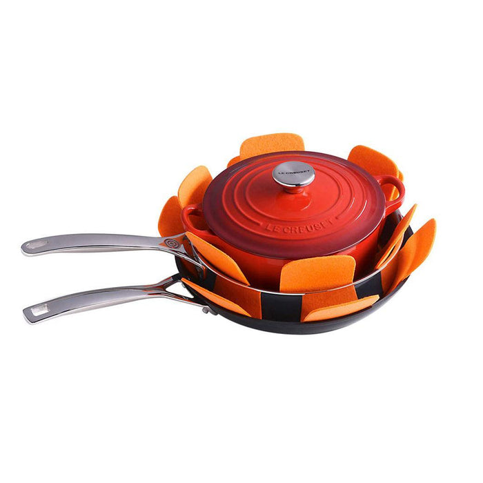 2 orange Le Creuset Felt Pan Protectors being used to protect cookware that are stacked on each other on a white background