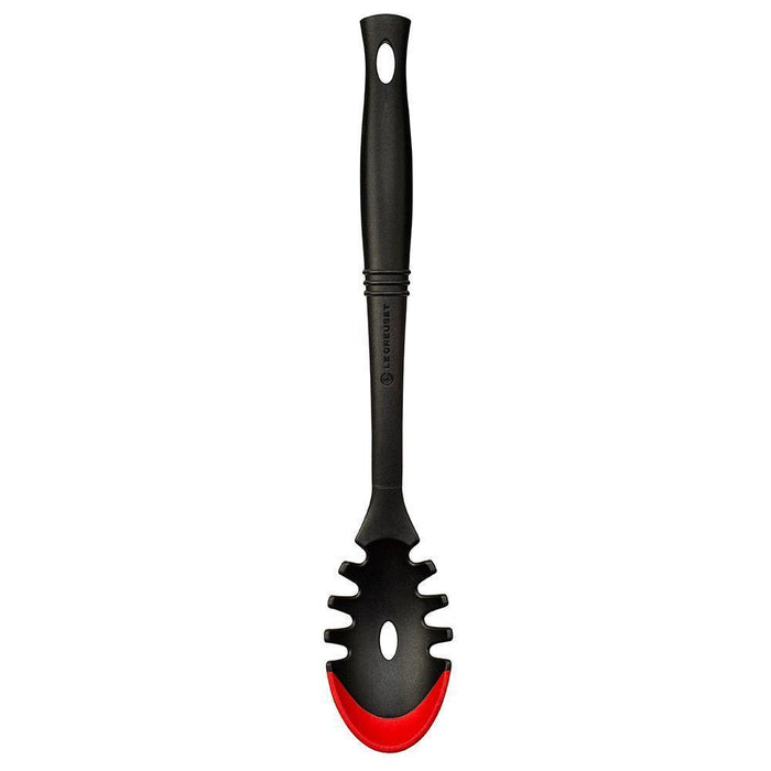 Cerise Le Creuset Revolution Bi-Material Pasta Spoon displayed vertically on a white background