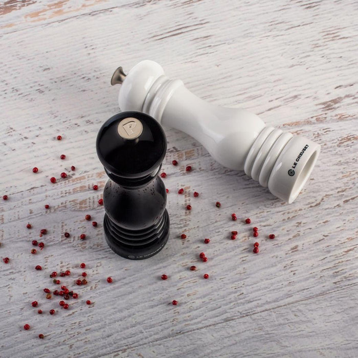 Le Creuset Salt and Pepper Mill Set of white and black displayed on a white wooden surface