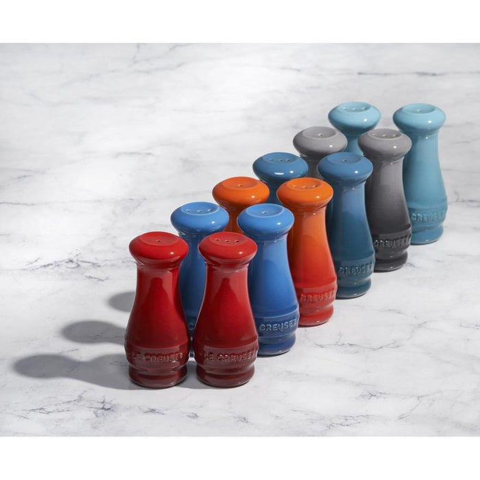 An assortment of colors of Le Creuset Salt and Pepper Shaker Set of Two displayed on a marble surface