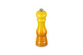 A yellow to orange gradient pepper mill with a silver metal top, centered on a plain white background.