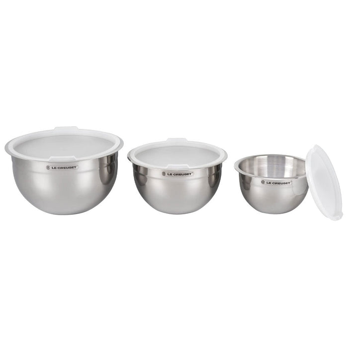 Set of 3 Le Creuset stainless steel mixing bowls with lids displayed in a row on a white background