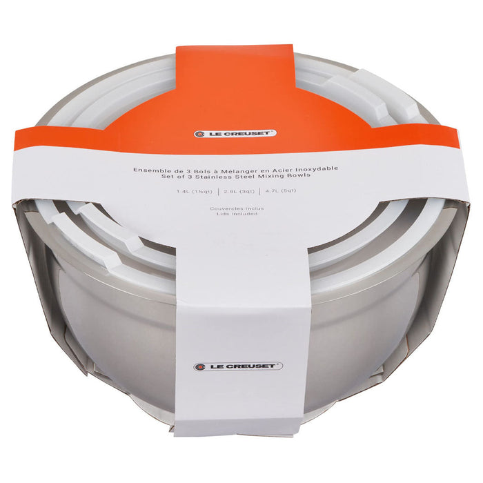 Set of 3 Le Creuset stainless steel mixing bowls with lids inside packaging displayed on a white background