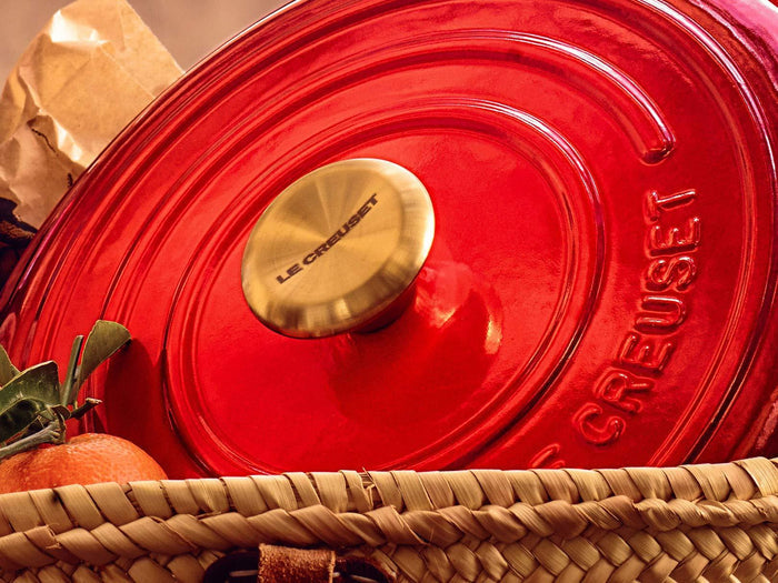 Cerise Le Creuset lid with Le Creuset Signature Gold Knob in a basket