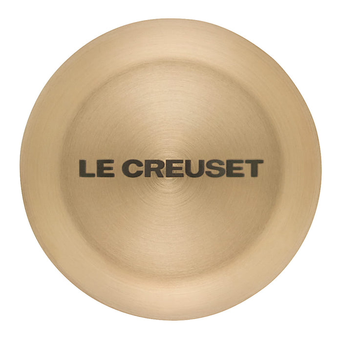 Top view of light gold knob with 'Le Creuset' branding on a white background