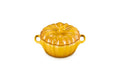 A glossy yellow-orange ceramic lidded casserole dish shaped like a pumpkin, featuring two side handles and a ribbed surface, set against a plain white background.