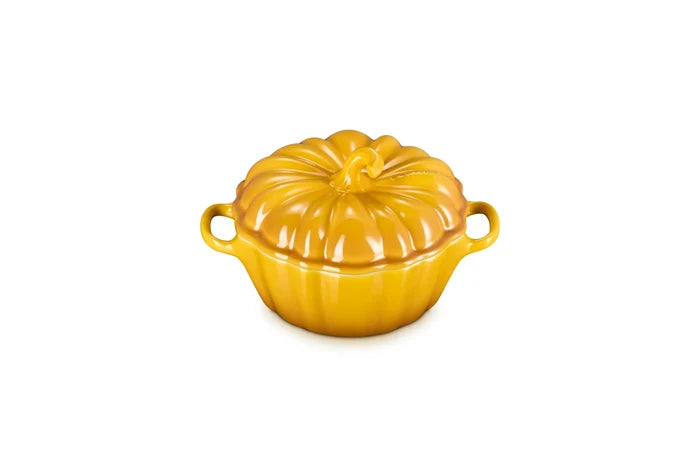 A glossy yellow-orange ceramic lidded casserole dish shaped like a pumpkin, featuring two side handles and a ribbed surface, set against a plain white background.