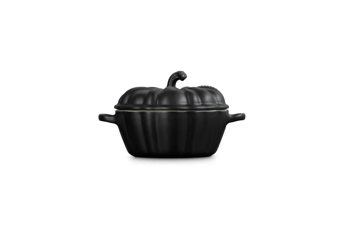 Side view of a black cast-iron pumpkin-shaped lidded cocotte with side handles, shown on a plain white background.