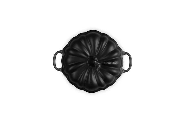 A black enameled cast iron Dutch oven lid with a ribbed pumpkin-like design and side handles, shown from a top-down view on a white background.