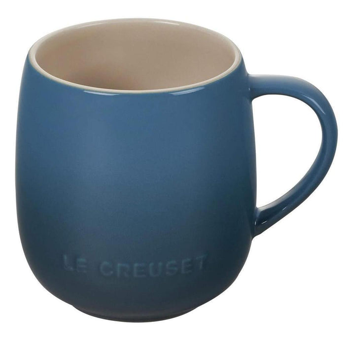 Blue mug with beige interior on a white background, featuring Le Creuset branding.