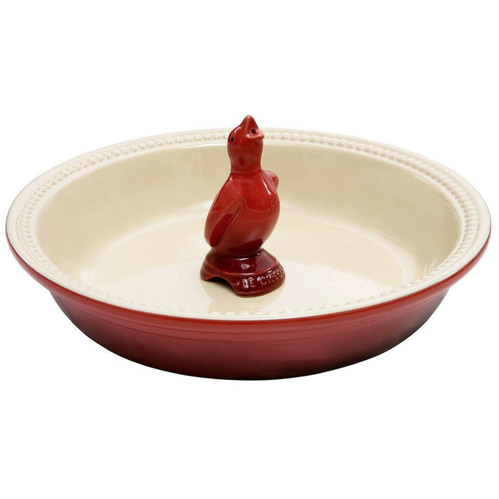 Cerise Le Creuset Stoneware Pie Bird in the middle of a cerise Le Creuset stoneware pie cookware displayed on a white background