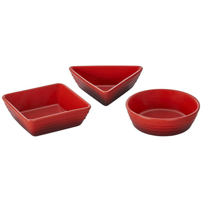 Set of 3 cerise Le Creuset stoneware tapas dishes of different shapes displayed on a white background