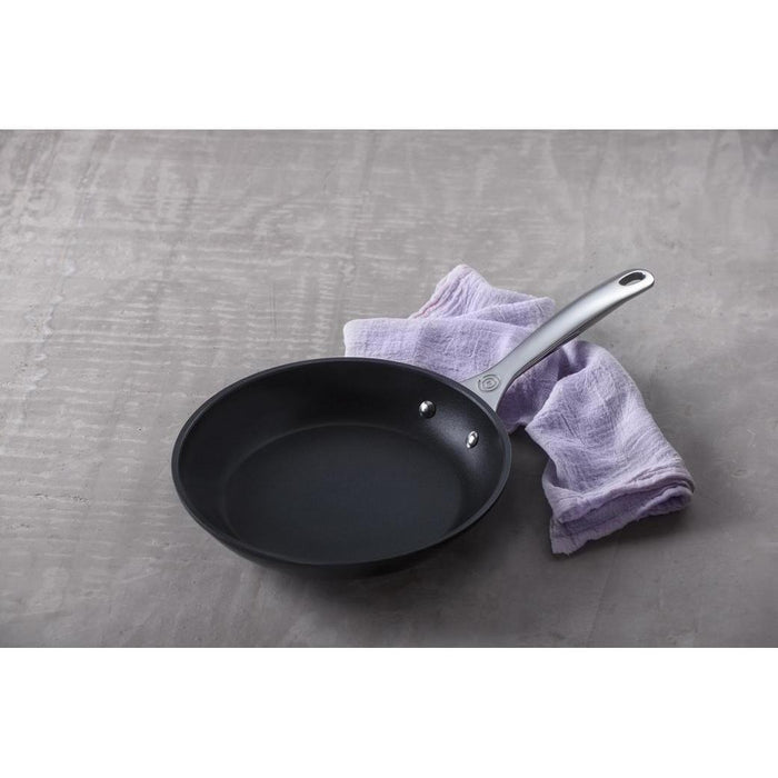 11 inch Le Creuset Toughened Nonstick Fry Pan next to a purple cloth displayed on a grey background
