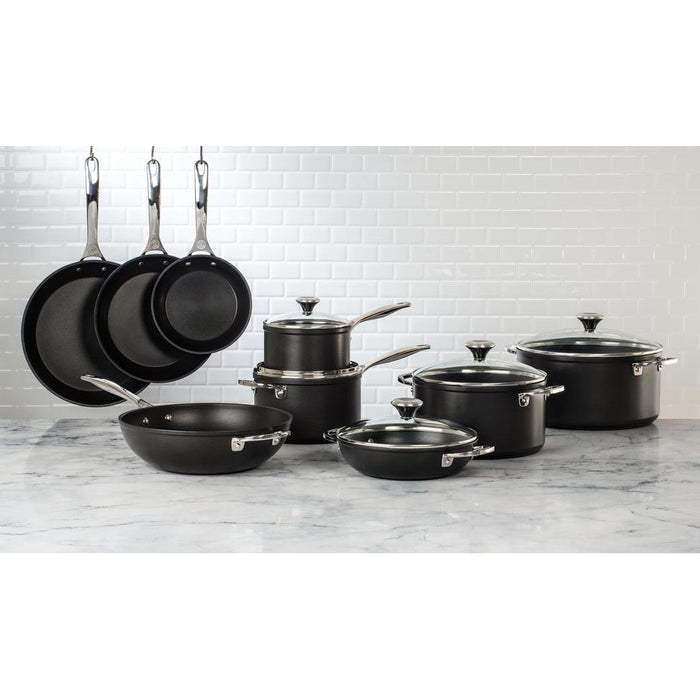 Set of Le Creuset toughened nonstick cookware displayed on a marble countertop