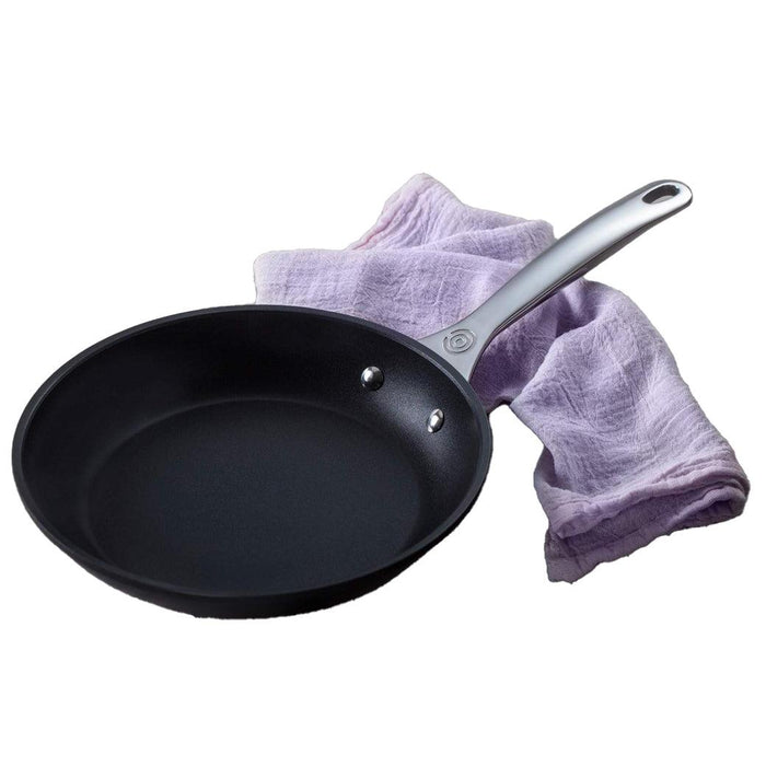 Le Creuset Toughened Nonstick PRO fry pan next to a purple cloth displayed on a white background