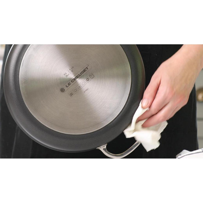Top view of someone wiping the bottom of Le Creuset Toughened Nonstick PRO 3.5 qt. Sauté Pan