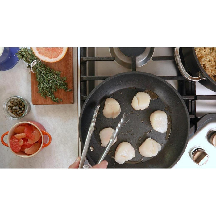 Someone cooking scallops on Le Creuset Toughened Nonstick PRO 6.3 qt Stockpot with Glass Lid placed in a kitchen setting