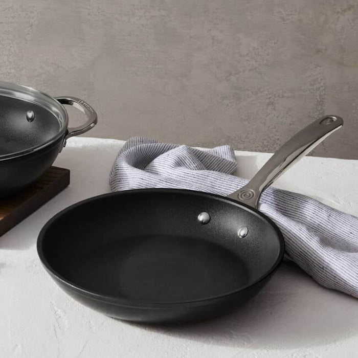 Black frying pan on a white surface with a gray background