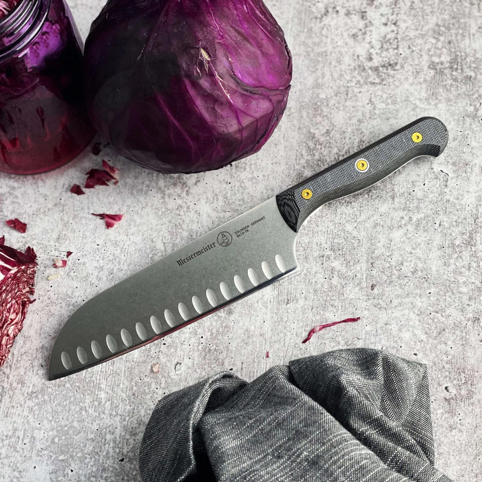 7 inch santoku knife next to jar, napkin, and red cabbage on a grey countertop