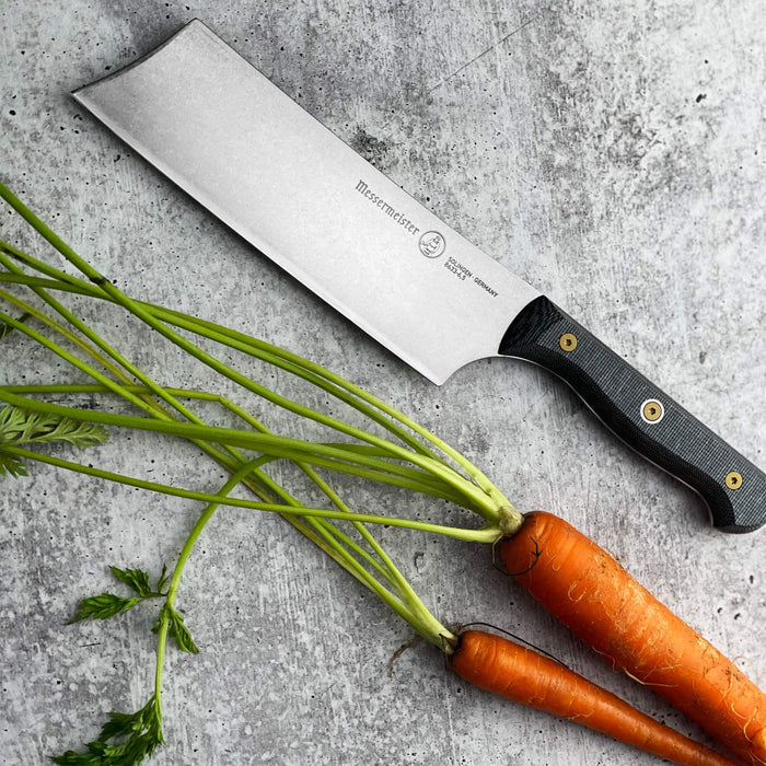 6.5 inch santoku knife next to carrots displayed on a grey surface
