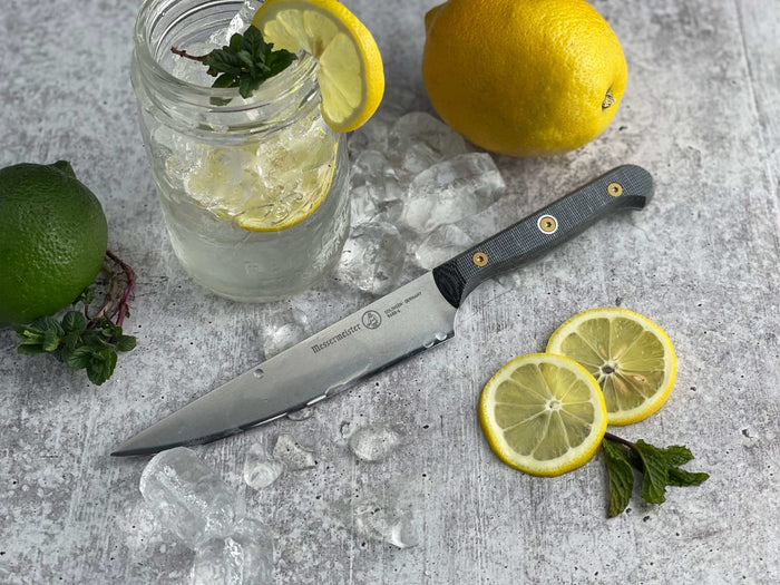 6 inch utility knife next to jar of water and ice with lemon and wine displayed on a grey surface
