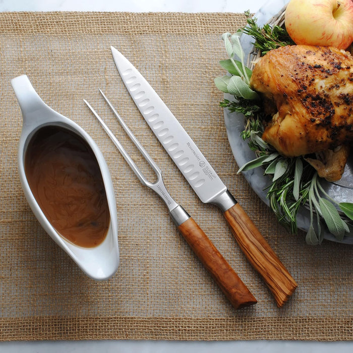 Roasted chicken with carving utensils and a gravy boat on a woven mat