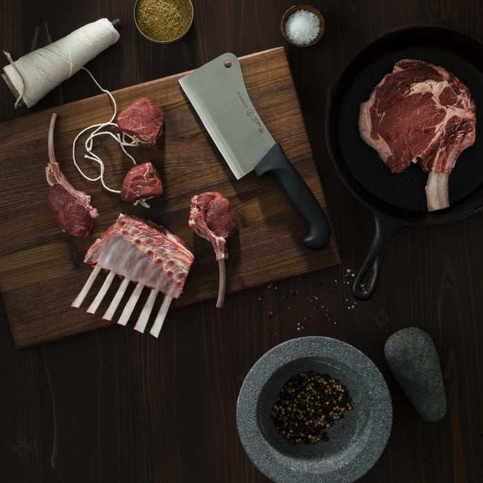 6 inch cleaver next to assortment of meats, spices, and seasonings displayed on cutting board and a wooden surface