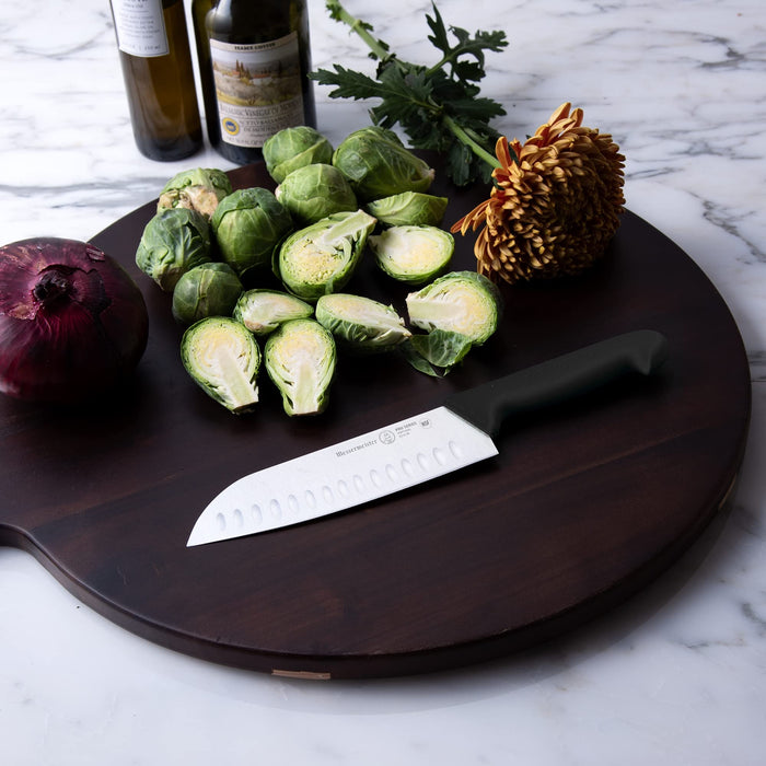 7 inch Santoku knife next to vegetables and flower sitting on a wooden board displayed on a marble countertop