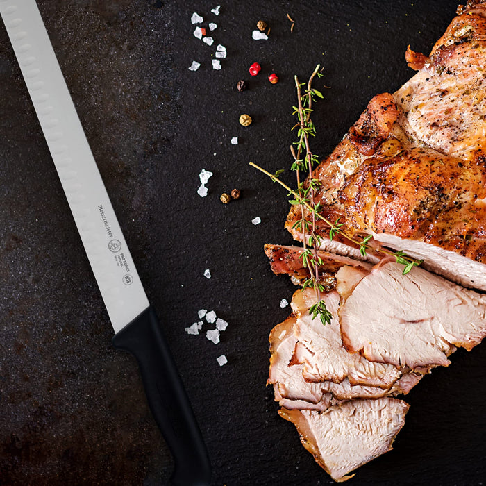 12 inch carving slicing knife next to a carved white meat displayed on a black background