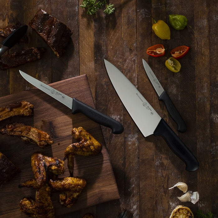 3 knifes next to chicken and brisket on a wooden countertop
