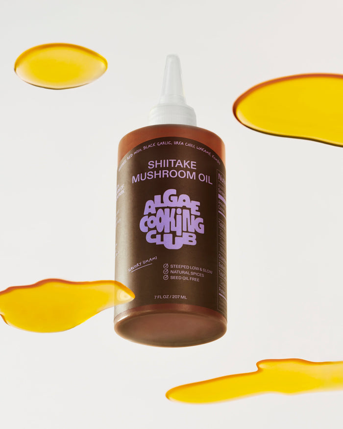 Bottle of Shiitake Mushroom Oil from Algae Cooking Club with oil droplets on a white background