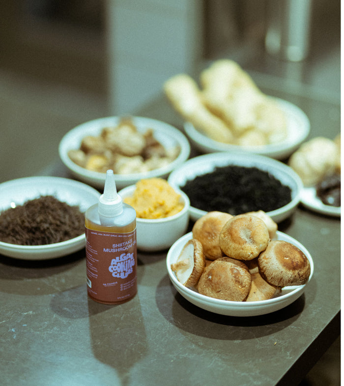Assorted food items including mushrooms, bread, and a bottle of sauce on a table.