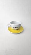 White teacup and saucer with yellow accent on a white background