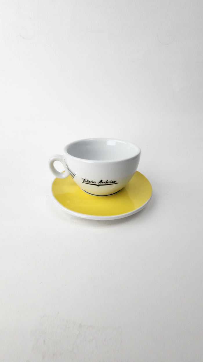 White teacup and saucer with yellow accent on a white background