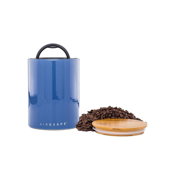 Blue air tight container with black handle and lid, with coffee beans on a white background.
