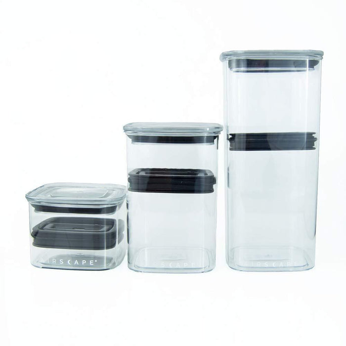 Set of clear glass storage containers with black lids on a white background