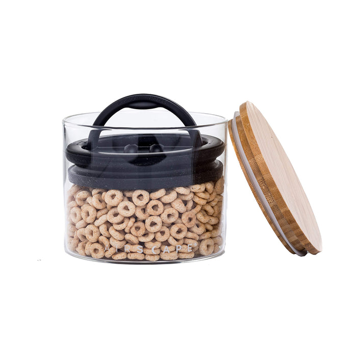 Small glass airscape container with an airtight lid and a bamboo lid on a white background