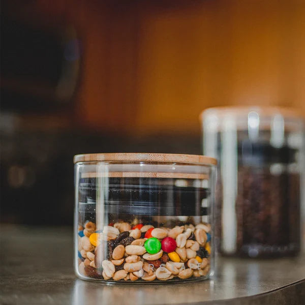 Small glass airscape filled with trail mix in a kitchen setting with a airtight lid and a bamboo lid