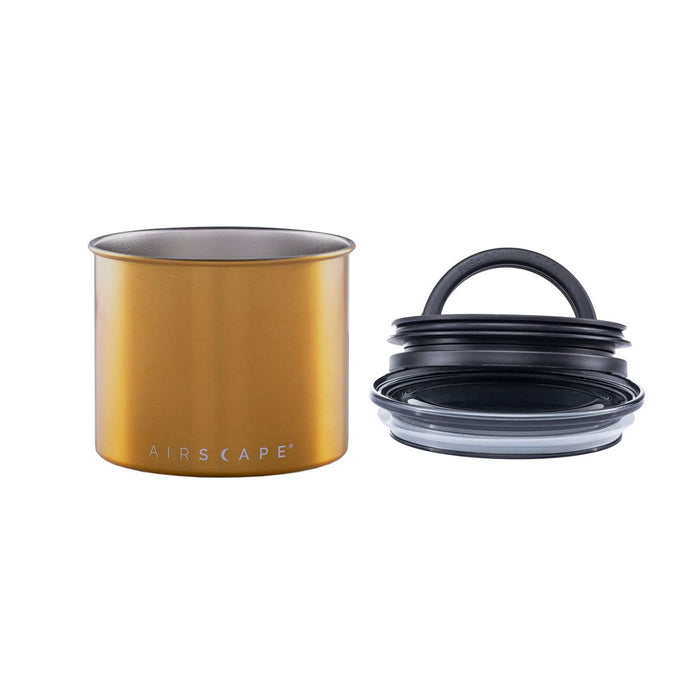 Brass-colored coffee canister with lid on the side on a white background