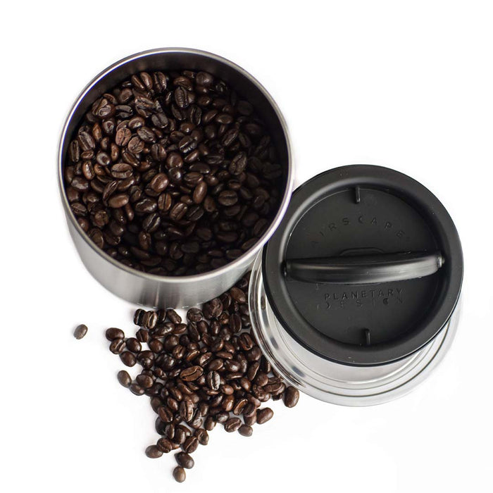 Top view of Brushed steel coffee canister with lid and coffee beans on a white background