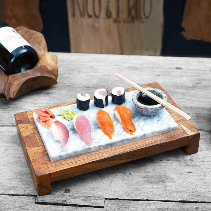 A sushi server featuring a rectangular teak wood base with an inset marble top, presented with sushi rolls, sliced fish, and chopsticks on the marble surface.
