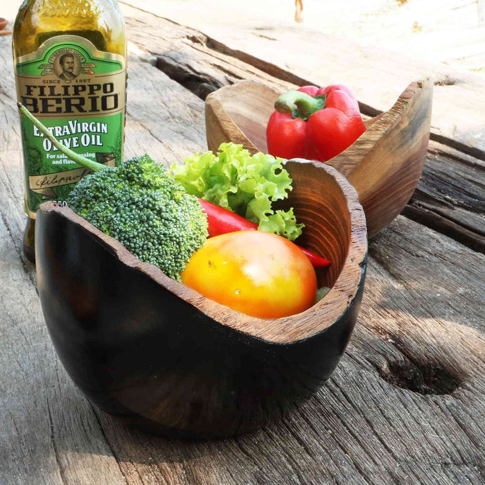 2 Rico & Plato adagio teak bowl one with black exterior and wooden exterior with fruit and vegetables inside placed on wooden surface