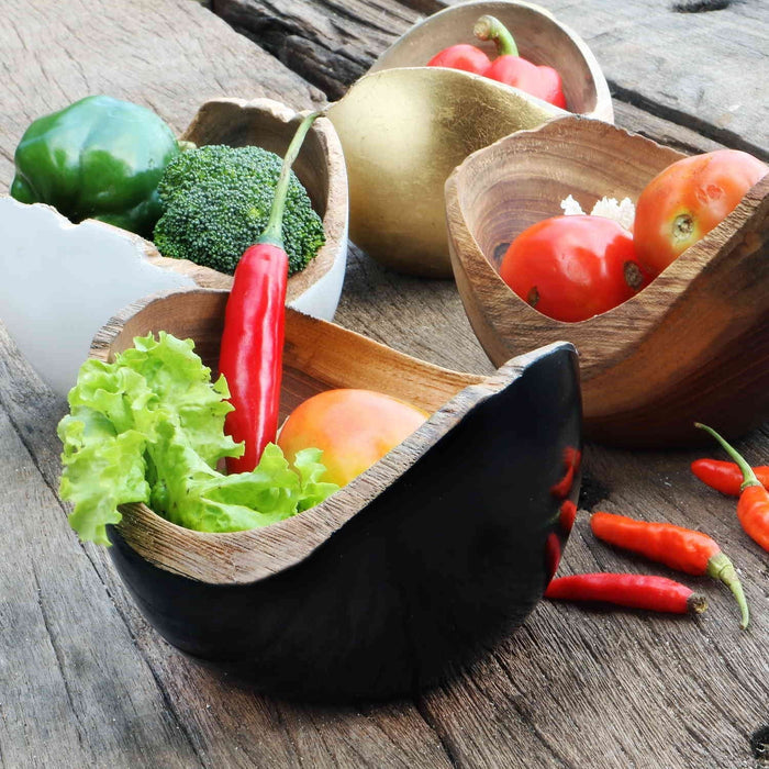 4 Rico & Plato adagio teak bowl with black, white, gold, and wooden exterior with fruits and vegetables inside placed on a wooden surface