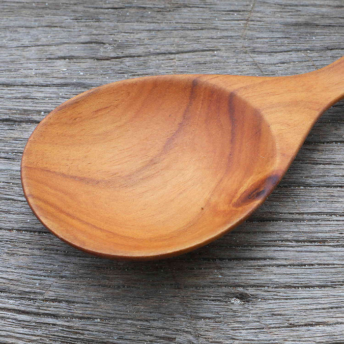 Close up of spoon of Rico & Plato almira teak spoon on a wooden surface