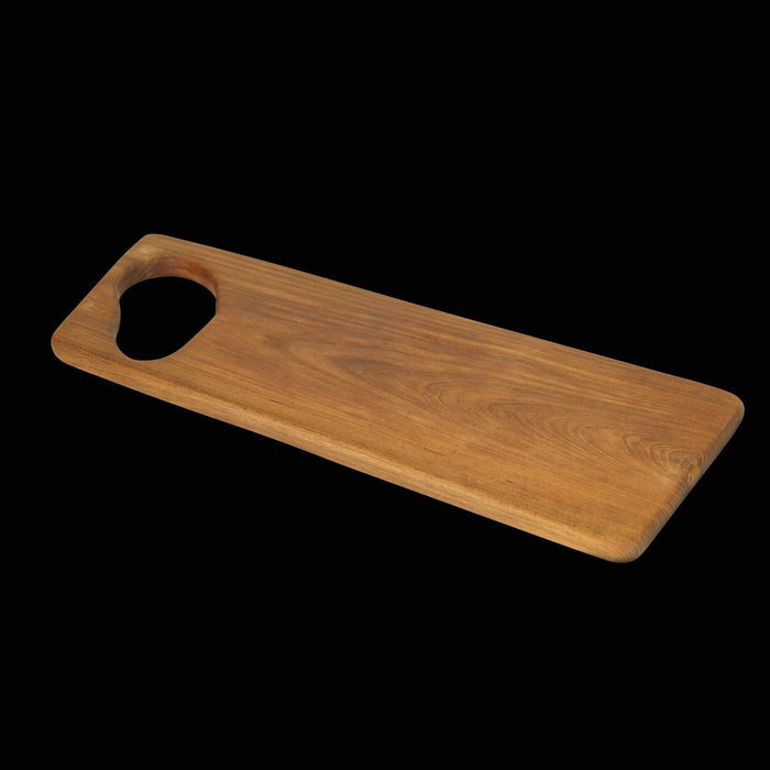 Teak cutting board with hole for handle displayed on a black background