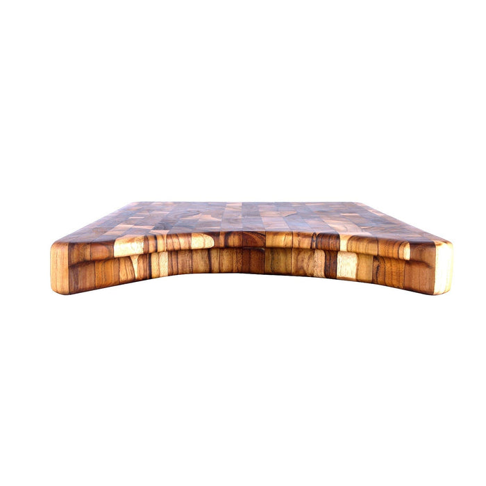 Side view of end grain teak cutting board with indent for a plate displayed on a white background