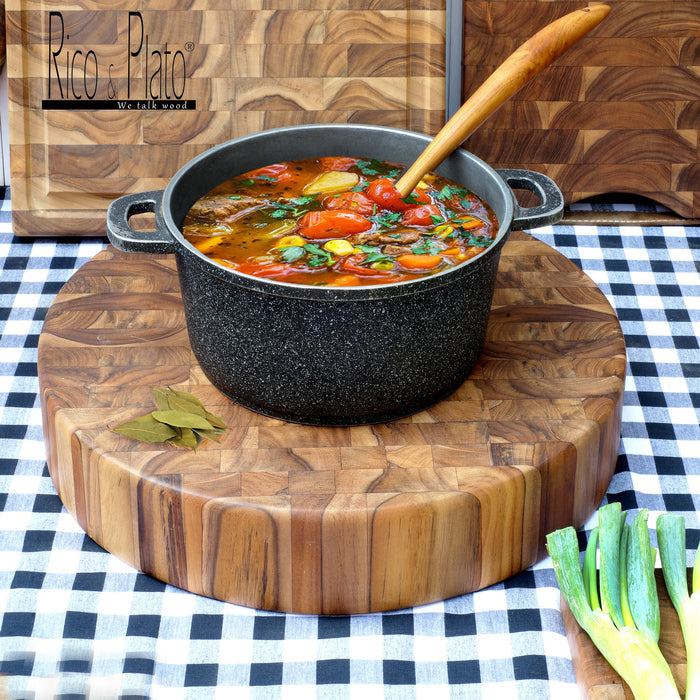 Rico & Plato Bayleaf and teak chopping board with a pot full soup and wooden spoon on a black and white checkered surface and end grain cutting boards in the back